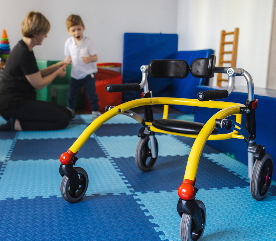 Young boy with cerebral palsy participates in physical therapy assisted by a therapist in a vibrant rehabilitation environment using open frame walker